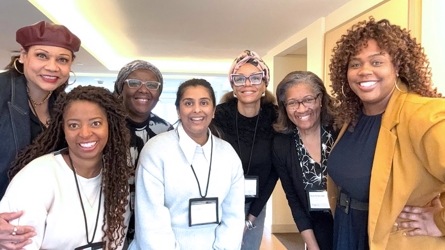 A group of diverse individuals in professional clothing, smiling at the camera.
